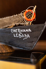 Decorative miniature boat featuring a lifebuoy and fishing net, evoking a charming nautical theme....