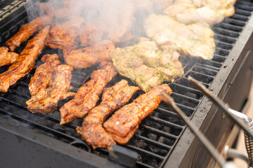 Meat is being cooking on a barbecue. Smoke is rising. It looks really delicious. Outdoor concept.