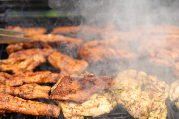 Meat is being cooking on a barbecue. Smoke is rising. It looks really delicious. Outdoor concept.