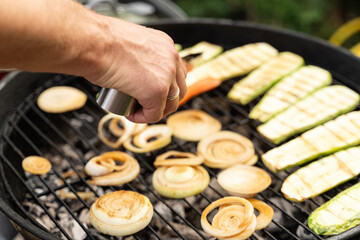 Vegetables cooking on a barbecue. Zucchini, carrots and onion. Smoke is rising. It looks really delicious. Outdoor concept.