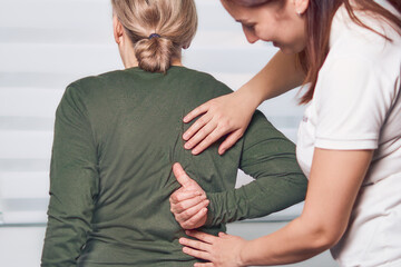Female doctor hands doing physical therapy on senior patient's back. Chiropractor examining senior...