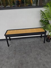 This image features a stylish minimalist bench with a sleek black frame and a woven rattan seat,...