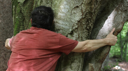 man hugging a tree in the woods symbol of connection with nature and empathy of the natural...
