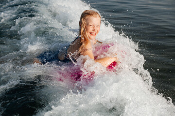 A girl with an inflatable ring getting splashed by a foamy wave — playful summer moment.