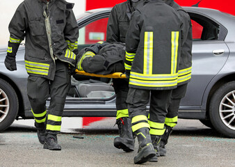 Firefighters with stretcher to rescue injured person by removing them from car after road accident