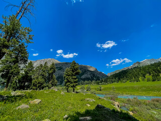 Beautiful mountain valley near Rainbow Lake, Astore, Pakistan. Features a flowing river, lush green...