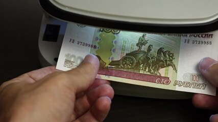 Examination of russian ruble (RUB) cash money with UV counterfeit detector. Concept of authenticity check, fight against counterfeiting of banknotes, anti fraud measures in Russia. Close up view.