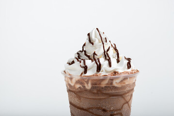 Chocolate milkshake served in a clear glass on a white background. Isolated drink