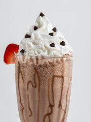 Chocolate milkshake served in a clear glass on a white background. Isolated drink.