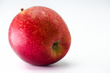 Bright red apple resting on a white surface showcasing its vibrant color and smooth texture