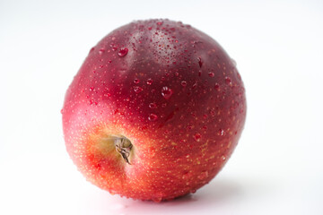 Fresh red apple with water droplets on a white background highlighting its natural shine and texture