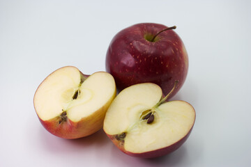 Red apples cut in half on a white background showcasing their juicy interior and vibrant skin color