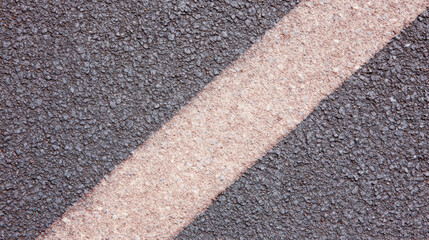 Fototapeta premium A close up view shows a diagonal beige painted line separating fresh dark asphalt creating a modern textured street or road design and pattern aesthetic.