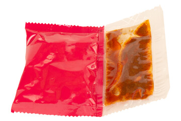 Red instant noodle seasoning packet on white background