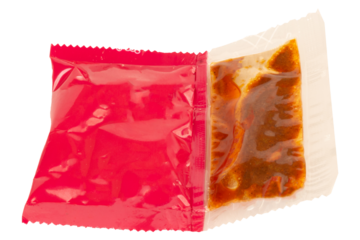 Red instant noodle seasoning packet on white background