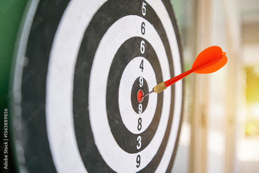 Poster dart hitting the bullseye on a dartboard for precision accuracy and achieving goals in games sports 