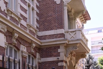 Eclectic brick building facade with white stone balcony, carved corbels, arched windows, and classical decorative details featuring Renaissance Revival and Baroque Revival elements © Visual Voyager