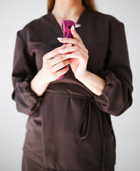 Close-up of a woman holding a pink otoscope in brown medical uniform, demonstrating professional healthcare tools.