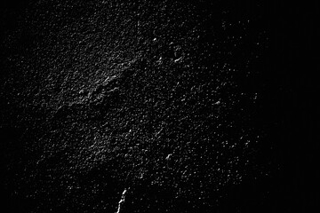 Speckled Rough plastering grunge wall. Shabby grainy noise dusted vintage abstract structure. Grungy surface. Retro gritty effect overlay. Black background