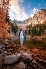 Waterfall plunging into a lake in the rugged mountains during autumn