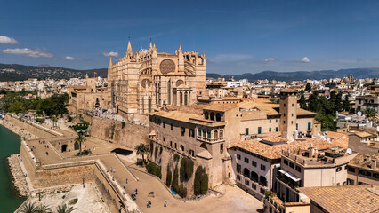 Naklejka premium An aerial view of Palma de Mallorca showcasing its grand cathedral, surrounded by historic buildings and coastal defenses, under a clear blue sky