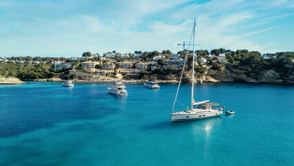 An aerial panorama reveals a stunning bay with crystal-clear azure waters, a vibrant sandy beach,...