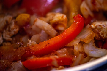 A close-up, high-detail macro shot capturing a woman preparing chicken sauté, showcasing sizzling ingredients, textures, and cooking action in a warm kitchen environment.