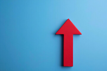 Fototapeta premium Isolated Red Arrow Pointing Upward on Blue Background Representing Growth, Progress, and Positive Direction in Business and Financial Markets
