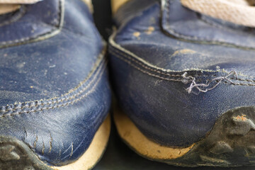 Detailed close-up of two worn-out sneaker toes showing cracked synthetic leather, frayed stitching,...