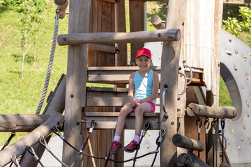 Happy and smiling caucasian child 7 8 years sitting on wood playscape
