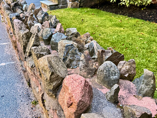 Colorful pointed stone fence along sidewalk with green lawn