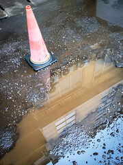 Dirty water puddles on the damaged asphalt road, exposing loose gravel and uneven surfaces. Bright...