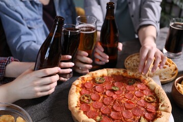 Friends with beer and snacks at grey table, closeup