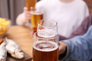 Friends having refreshing beer at home, closeup