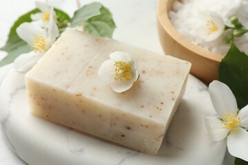Soap bar, sea salt and jasmine flowers on table, closeup