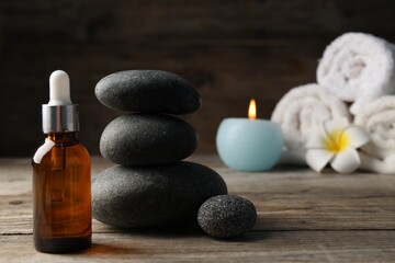 Composition with cosmetic product and spa stones on wooden table, closeup