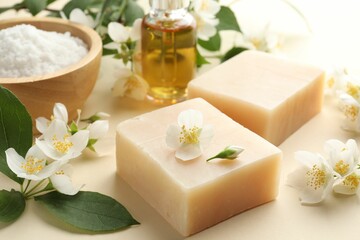 Soap bars, essential oil, sea salt and jasmine flowers on beige background, closeup
