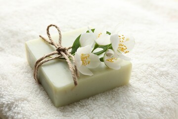 Soap bar and jasmine flowers on towel, closeup