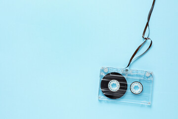 One audio cassette with magnetic tape on light blue background, top view. Space for text