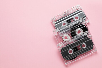 Audio cassettes with magnetic tapes on pink background, flat lay. Space for text