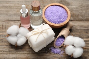 Soap bars, cosmetic products and cotton flowers on wooden table, above view