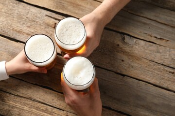 Friends with glasses of beer at wooden table, top view. Space for text