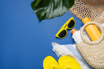 Beach accessories and palm leaf on blue background, flat lay. Space for text
