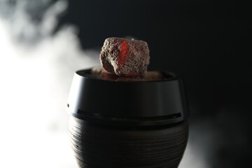 Smoldering charcoal cubes in hookah holder and smoke on dark background, closeup