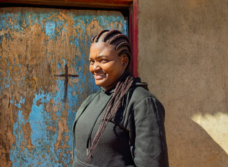 Africa village , african Christian woman with braids dreadlocks cornrow in the yard, in front of...