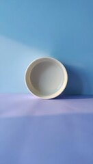 A Simple White Ceramic Bowl Sitting on a Purple Surface Against a Blue Wall