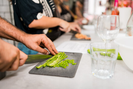 close up of hand cutting vegetebles during cooking class with group of people learning to cook - Powered by Adobe