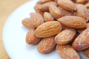 White Plate Full of Almonds Kernel Isolated on Wooden Table