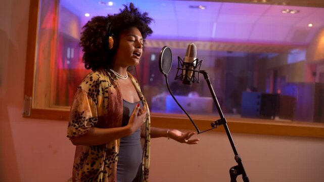 Female singer recording vocals in professional studio booth