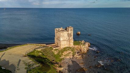 Casares Coastal Watchtower: An ancient watchtower stands on a rocky outcrop at the water's edge,...